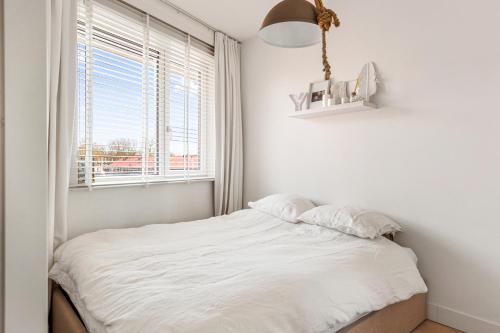 a white bedroom with a bed and a window at Atmospheric apartment Zaandam/Amsterdam in Zaandam
