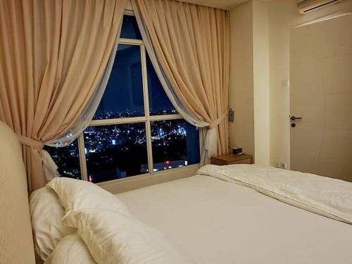 um quarto com uma cama branca e uma janela em Central Park Residence Podomoro Condo for Four em Jakarta