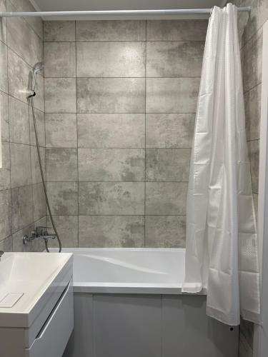 ein Badezimmer mit einer weißen Badewanne und einem Waschbecken in der Unterkunft ЖК Ауэзов in Kökschetau