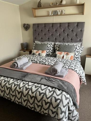 a bedroom with a large bed with a black and white bedspread at Modern, Spacious 2 bedroom caravan - Thorpe Park Haven, Cleethorpes in Cleethorpes