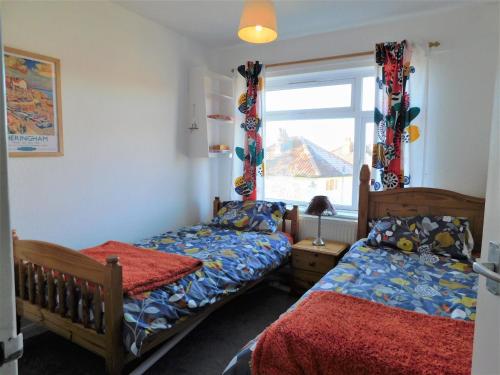 a bedroom with two beds and a window at Berry Cottage in Sheringham
