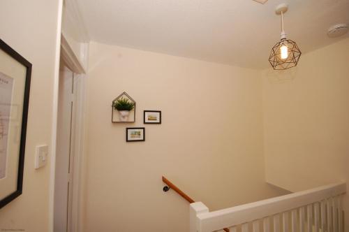 un couloir avec un escalier doté d'une lampe suspendue dans l'établissement Berry Cottage, à Sheringham