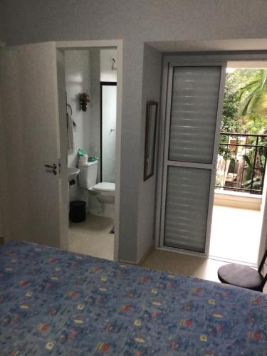 a bedroom with a bed and a bathroom with a door at Apto. aconchegante in Ubatuba