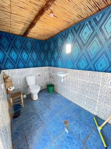 bagno piastrellato blu con servizi igienici e lavandino di Mhamid Sahara Golden Dunes Camp - Chant Du Sable a Mhamid