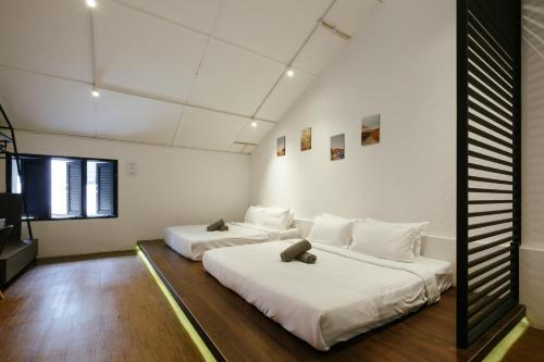 two beds in a room with white walls and wood floors at Kangsar Inn 73 in George Town