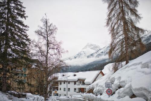 a building covered in snow with trees and mountains at Chasa Grusaida, Vulpera in Vulpera