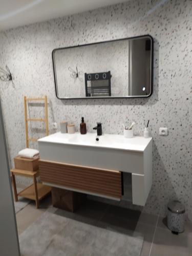 La salle de bains est pourvue d'un lavabo blanc et d'un miroir. dans l'établissement Charme et élégance au cœur d'un village provençal, à Pignans