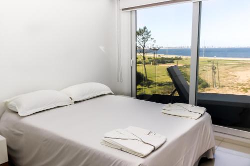 1 dormitorio con cama blanca y ventana grande en Azure Beach, en Punta del Este