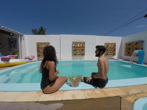 a man and a woman sitting in a swimming pool at Barra Grande Pousada in Maragogi