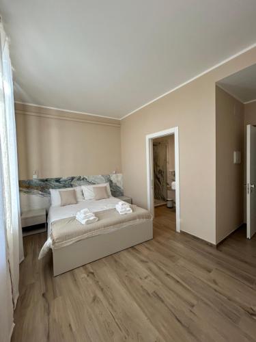 een witte slaapkamer met een bed en houten vloeren bij Breccia Nel Mare in Carrara