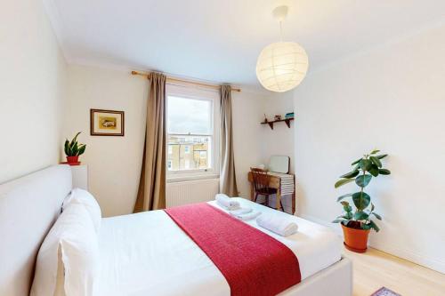 a bedroom with a bed with a red and white blanket at Stunning 1 bed apartment in Fulham in London