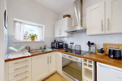 eine Küche mit weißen Schränken und einer Arbeitsplatte in der Unterkunft Stunning 1 bed apartment in Fulham in London