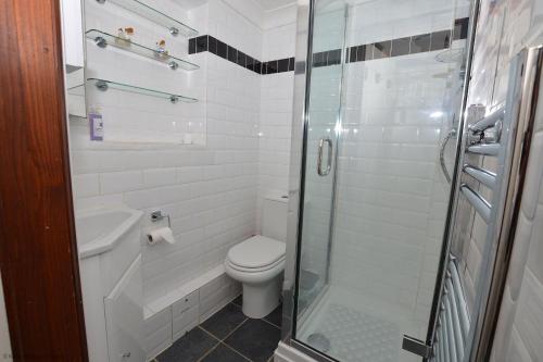 a bathroom with a toilet and a glass shower at Cockleshell Cottage in Sheringham