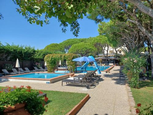 una piscina con tumbonas y sombrilla en Hotel Viña del Mar Pineta, en Lido di Jesolo