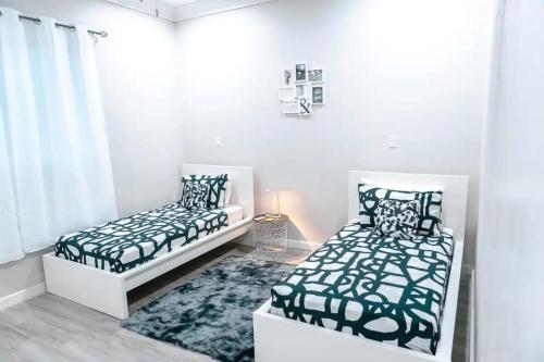 Cette chambre blanche comprend 2 lits et un tapis. dans l'établissement EXCLUSIVE Modern Apartment in Nasáu, Bahamas, à Nassau