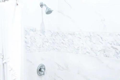 d'une baignoire blanche avec un pommeau de douche. dans l'établissement EXCLUSIVE Modern Apartment in Nasáu, Bahamas, à Nassau