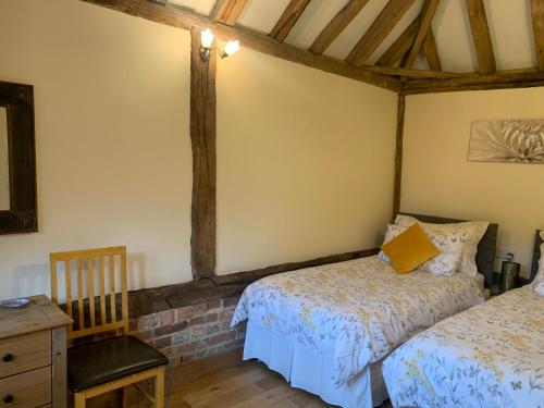 a bedroom with two beds and a table and a chair at NEW Cosy cottage - Lake view & Log Burner - Dog proof garden in Rolvenden
