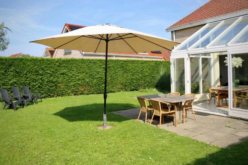 una mesa y sillas bajo una sombrilla en un patio en Hello Zeeland - Vakantiehuis Schelde 148, en Breskens