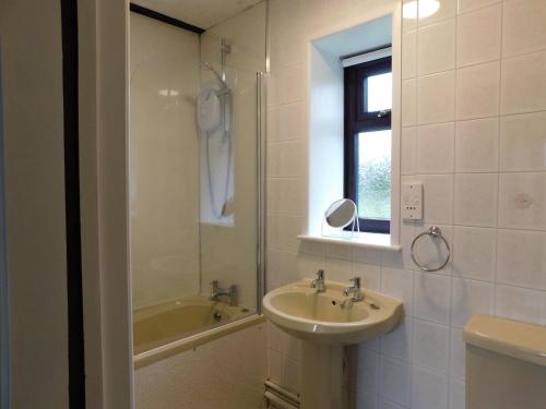 een badkamer met een wastafel, een spiegel en een bad bij Paddock Bungalow in Mundesley