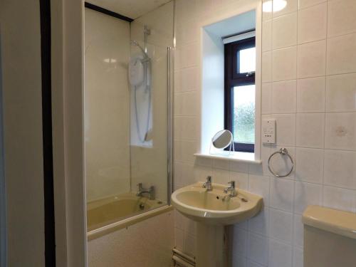 a bathroom with a sink and a mirror and a tub at Paddock Bungalow in Mundesley