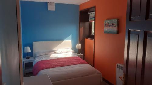 een slaapkamer met blauwe en oranje muren en een bed bij Paddock Bungalow in Mundesley