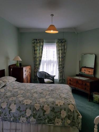 a bedroom with a bed and a dresser and a mirror at Old Schoolyard Cottage in Sheringham