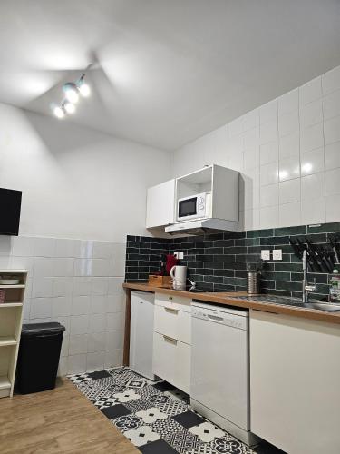 - une cuisine avec des appareils électroménagers blancs et du carrelage noir et blanc dans l'établissement #6 Petite Maison avec petit jardin proche du Métro, à Bagnolet