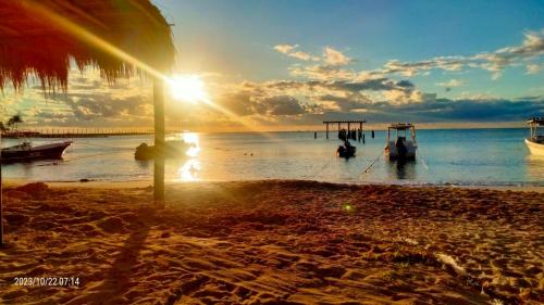 een zonsondergang op een strand met boten in het water bij LYJ HOTEL Hab 21 in Playa del Carmen