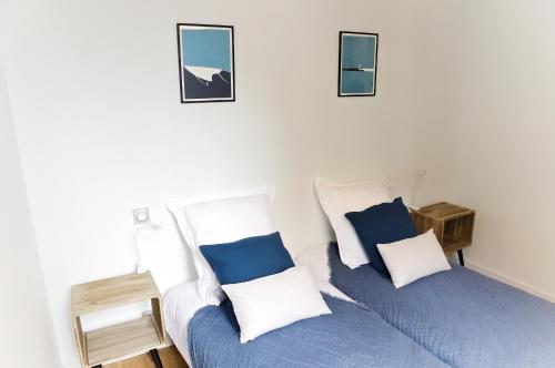 una camera con 2 letti con cuscini blu e bianchi di Belle Vue - Appartement 2 chambres avec parking a Bordeaux