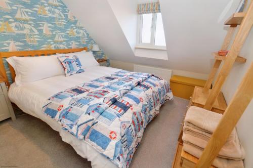 a bedroom with a bed with a blue and white quilt at Gull View in Sheringham