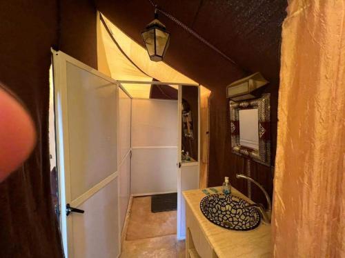 a bathroom with a sink and a white door at Bivouac Le Ciel Bleu in Erfoud