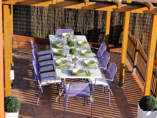 een tafel met paarse stoelen en borden op een terras bij Villa Sitges El Olivo High Comodity AC Pool Heated Optional Real Garden Pool XXL in Olivella