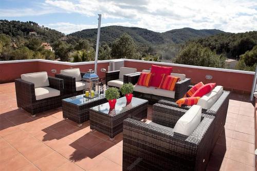 een patio met rieten stoelen en tafels op een dak bij Villa Sitges El Olivo High Comodity AC Pool Heated Optional Real Garden Pool XXL in Olivella