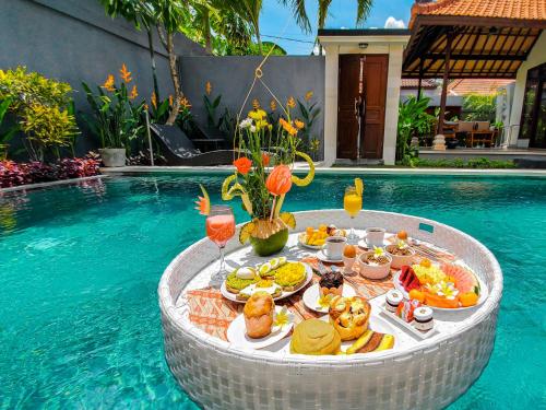 a tray of food on a table next to a swimming pool at AmaLuna II Villa in Seminyak in Seminyak