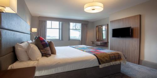 a hotel room with a bed and a flat screen tv at The Yorkshire Hotel in Harrogate