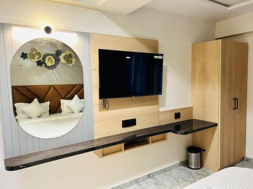 Habitación con TV en la pared y espejo. en Hotel Marigold Naroda en Ahmedabad