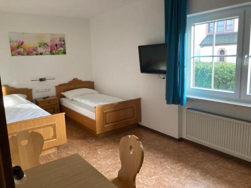 a small room with two beds and a window at Pension Dorfengel in Berolzheim