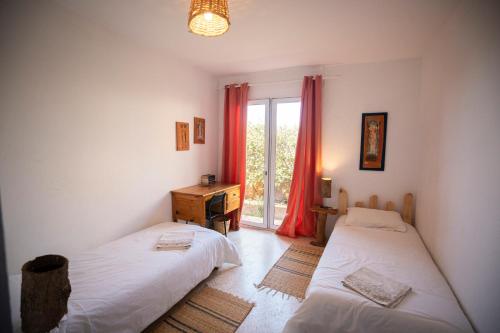 - une chambre avec 2 lits, un bureau et une fenêtre dans l'établissement Satya Surf Camp, à Tamaris