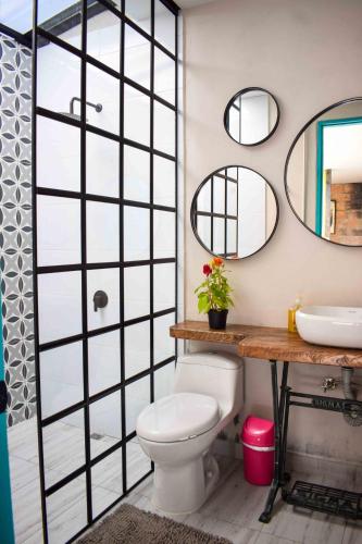 a bathroom with a toilet and a sink and mirrors at CASA HOTEL LAS HORTENSIAS in Jardin