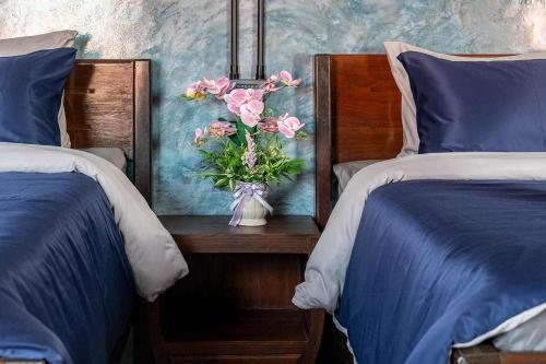 a vase of flowers on a table between two beds at Smilingface guesthouse in Sukhothai
