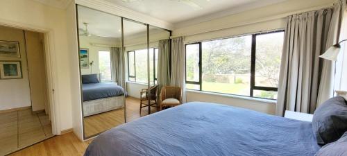 a bedroom with a bed and a large window at Shelly Beach beachfront apartment in Shelly Beach