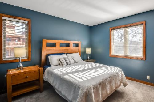 a blue bedroom with a bed and two windows at Cozy Illinois Abode with Deck and Grill, Near Golfing! in Galena