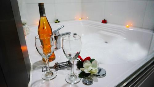 a bottle of wine and two wine glasses on a bath tub at Hotel Bacata Plaza in Zipaquirá
