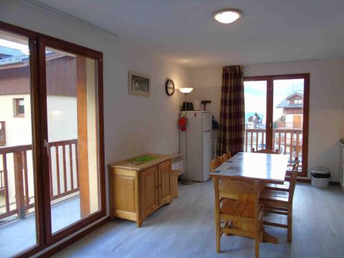 une cuisine avec une table et un réfrigérateur dans l'établissement Appartement cosy à Valfréjus, 200m des pistes, balcon ouest, 6 pers, cuisine équipée, draps inclus - FR-1-561-23, à Valfréjus