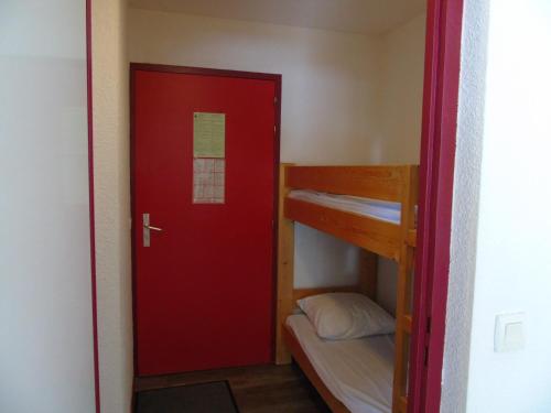Cette chambre dispose d'une porte rouge et de lits superposés. dans l'établissement Appartement cozy 6 pers., 50m écoles ski, WIFI, parking, balcon - FR-1-561-18, à Valfréjus