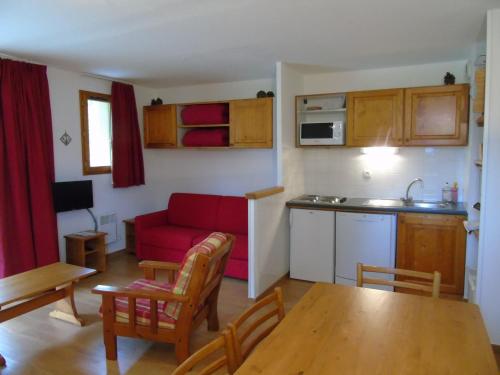un salon avec un canapé rouge et une cuisine dans l'établissement Appartement cosy 2 pièces avec terrasse, proche télésièges et commerces, idéal pour 6 personnes! - FR-1-561-78, à Valfréjus