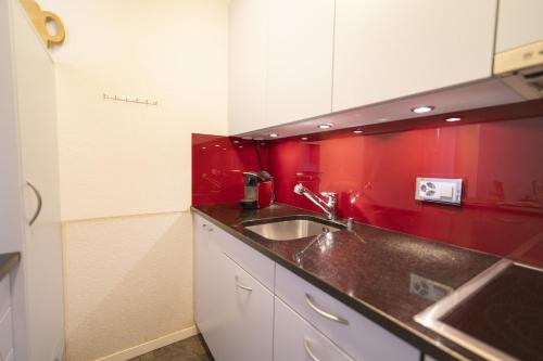 a kitchen with a sink and a red wall at Feriensiedlung Trü 8 in Scuol