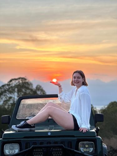 a woman sitting on the back of a truck with the sunset at Batur volcano sunrise jeep in Kubupenlokan