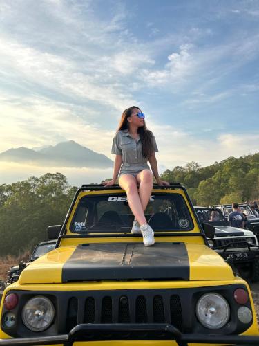 a woman sitting on the top of a car at Batur volcano sunrise jeep in Kubupenlokan