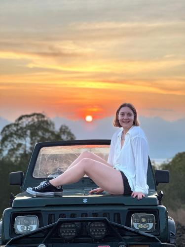 a woman sitting on the hood of a truck at Batur volcano sunrise jeep in Kubupenlokan